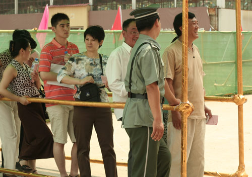 A security man talks with residents at the venue for a vote on demolishment and reconstruction of old buildings in Juixiaqiao Sub-district in Beijing, June 9, 2007. Local government and the real estate developer jointly organize the vote on Saturday to see if majority residents of over 5000 families accept the new compensation policy after failed attempts to reach an agreement through other ways. Both notary officials and supervisors are invited to monitor the vote that runs from 9 a.m. to 9 p.m. at six ballot booths. [Sun Yuqing/www.hwdly.com.cn]