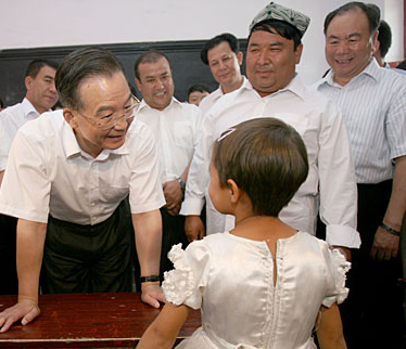 Chinese Premier Wen Jiabao (L) talks with a student at a bilingual kindergarten during his inspection tour to the northwestern Xinjiang Uygur Autonomous Region from last Thursday to Sunday. Wen Jiabao visited villages, schools, enterprises, hospitals and the Xinjiang production and construction corps of the army in a number of prefectures and cities to show his extensive care for local people's livelihood, education, medical service and the development of energy sources，Xinhua reported.Picture taken on August 16.[Xinhua]