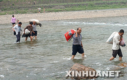 嵩縣木植街鄉(xiāng)的部分深山獨居戶涉水下山，準(zhǔn)備搬入新居（2002年6月26日攝）。 河南省嵩縣是國家扶貧工作重點縣。為徹底改變部分生活在深山區(qū)、被“行路難、用電難、吃水難、上學(xué)難、就醫(yī)難”困擾的村民的生活狀況，從2002年開始，嵩縣把“異地安置、搬遷扶貧”作為山區(qū)扶貧開發(fā)的切入點和深山群眾脫貧致富的途徑，有計劃、分期分批地把他們搬遷到小城鎮(zhèn)和交通便利的村莊。5年來，嵩縣通過多種形式，新建移民新村53個，遷出深山貧困群眾3238戶、13151人。 新華社記者 王頌攝 