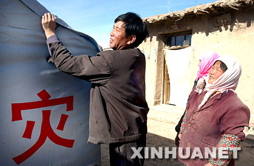 2003年11月12日，甘肅山丹縣李橋鄉(xiāng)劉莊村黨支部書記王升（左）在該村七社村民王金秀（右）家檢查抗震救災(zāi)帳篷密封情況。2003年10月25日，甘肅山丹縣發(fā)生6.1級地震后，該縣廣大黨員干部一直奮戰(zhàn)在抗震救災(zāi)第一線。 新華社發(fā) 