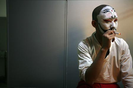 A Chinese artist smokes backstage before performing in a English version of the traditional Chinese opera Monkey King at a theatre in Shanghai December 8, 2006. Among the performers is Ghaffar Pourazar of Britain (not in photo), the first foreigner to complete the rigorous training at the Beijing Opera School and the National Academy. He is performing with Chinese artists from the International Centre for Beijing Opera, and other troupes, at their first show in Shanghai. 