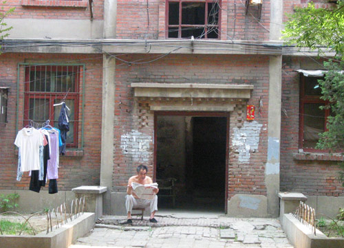 A Chinese man reads newspaper in Juixiaqiao Sub-district in Beijing, June 9, 2007. Local government in Jiuxianqiao and the real estate developer jointly organize the vote on Saturday to see if majority residents of over 5000 families accept the new compensation policy after failed attempts to reach an agreement through other ways. Both notary officials and supervisors are invited to monitor the vote that runs from 9 a.m. to 9 p.m. at six ballot booths. [Sun Yuqing/www.hwdly.com.cn]