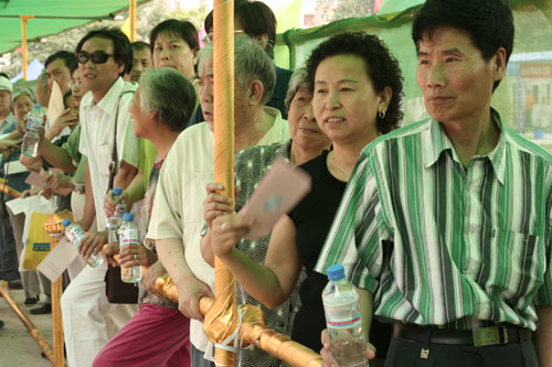 Residents wait to cast their votes on the demolishment and reconstruction of old buildings in Juixiaqiao Sub-district in Beijing, June 9, 2007. Local government and the real estate developer jointly organize the vote on Saturday to see if majority residents of over 5000 families accept the new compensation policy after failed attempts to reach an agreement through other ways. Both notary officials and supervisors are invited to monitor the vote that runs from 9 a.m. to 9 p.m. at six ballot booths. [Sun Yuqing/www.hwdly.com.cn]