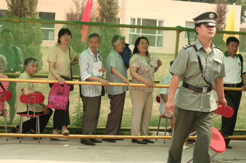 A security man carries a charir at the venue for a vote on demolishment and reconstruction of old buildings in Juixiaqiao Sub-district in Beijing, June 9, 2007. Local government and the real estate developer jointly organize the vote on Saturday to see if majority residents of over 5000 families accept the new compensation policy after failed attempts to reach an agreement through other ways. Both notary officials and supervisors are invited to monitor the vote that runs from 9 a.m. to 9 p.m. at six ballot booths. [Sun Yuqing/www.hwdly.com.cn]