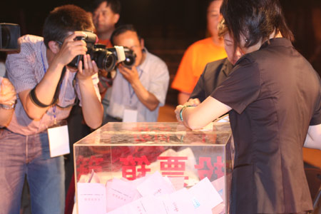 Photographers take the picture as two notary officials seal the balloting boxes after a voting on the housing demolition and compensation policy at Jiuxianqiao sub-district in Chaoyang District of Beijing, June 9, 2007. Some 3,711 families, about 57% of the 5,473 families, cast their votes on Saturday, with 2,451 votes for and 1,228 votes against the demolition and compensation plan. Thirty-two votes were invalid. [Sun Yuqing/www.hwdly.com.cn]